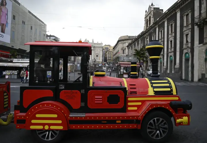 Czerwony pociąg turystyczny "Tourist Dream" na ulicach Katanii, idealny do zwiedzania Syrakuz.