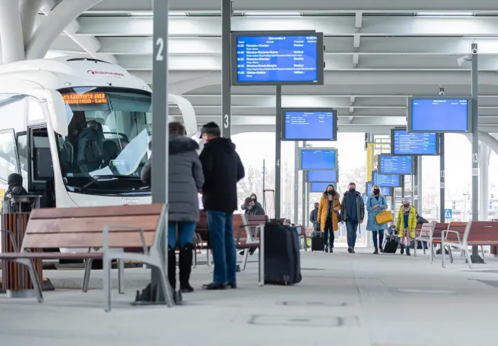 Na dworcu w Katowicach, przy tablicy z odjazdami, ludzie czekają na autobusy. Sprawdź rozkład, by dowiedzieć się, jak dojechać z dworca w Katowicach na Medyków.