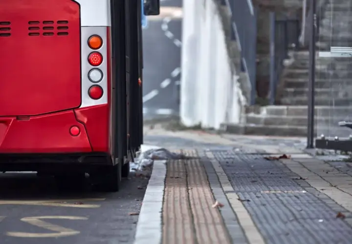 Czerwony autobus 74 stoi na przystanku. Widać jego tylne światła i część karoserii.