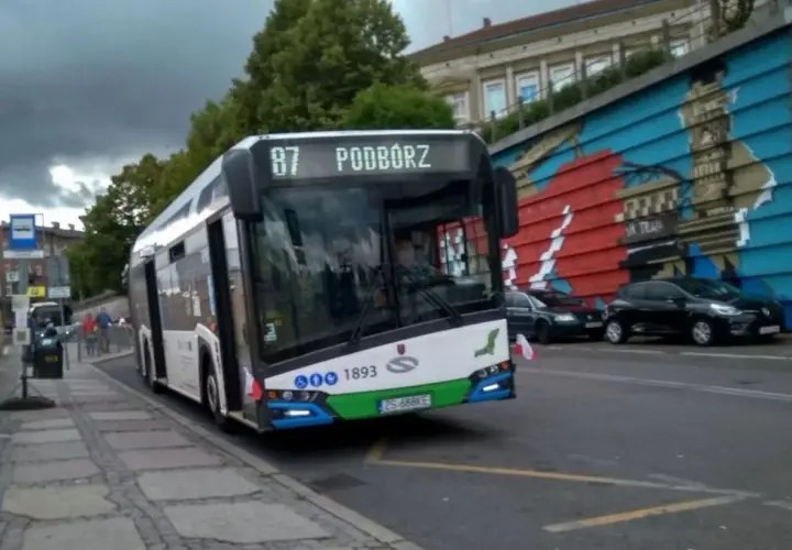 Autobus linii 87 w Szczecinie z napisem "Podwórze" na wyświetlaczu, zbliża się do przystanku.