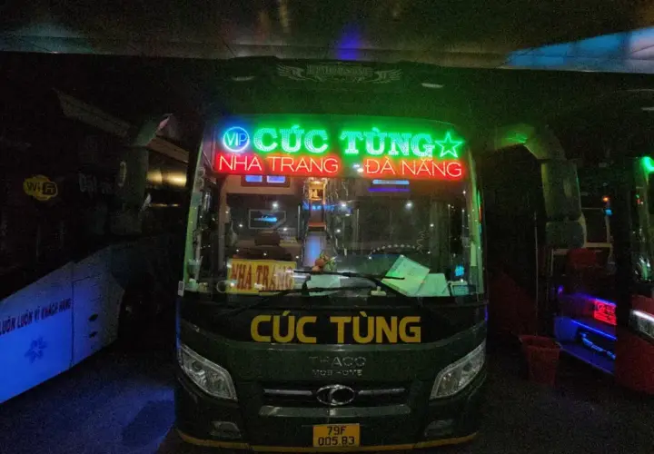 Zielony autobus nocny z neonowym napisem "CÚC TÙNG" i trasą Nha Trang - Da Nang.