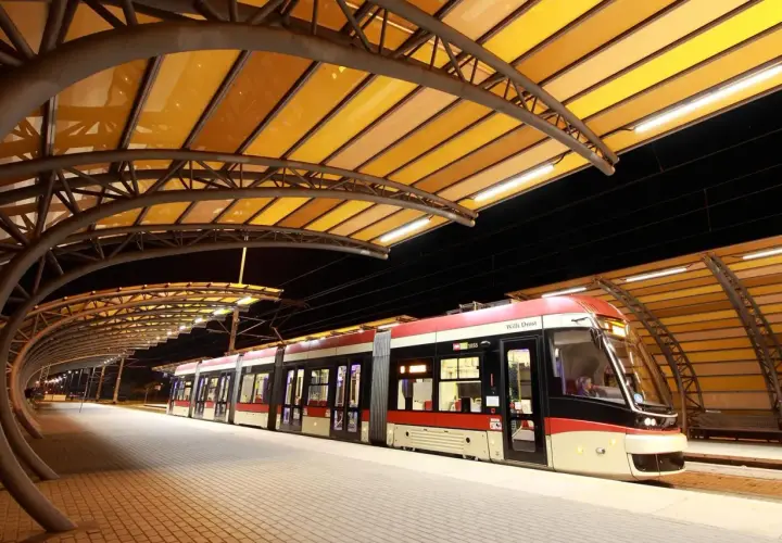 Nowoczesne gdynia tramwaje na peronie pod żółtą, łukowatą wiatą.
