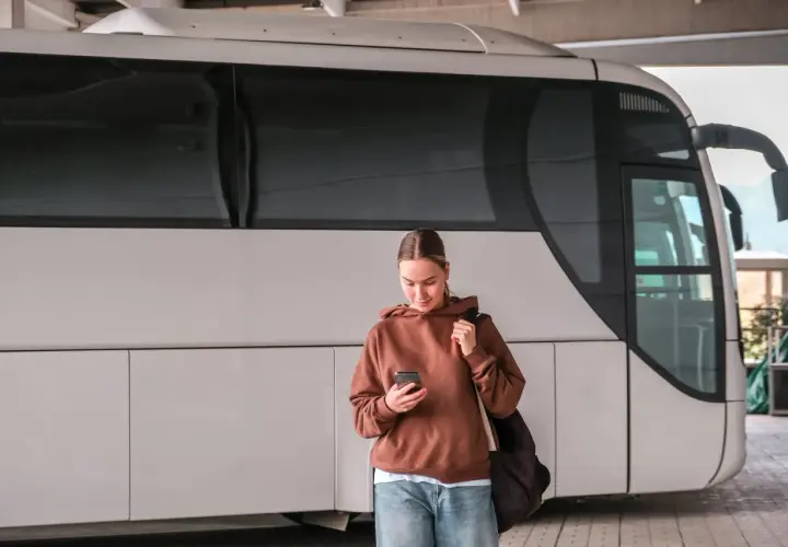 Młoda kobieta z telefonem czeka na autobus, który ma awarię taboru.