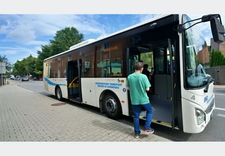 Biały autobus miejski z otwartymi drzwiami, wsiada pasażer.