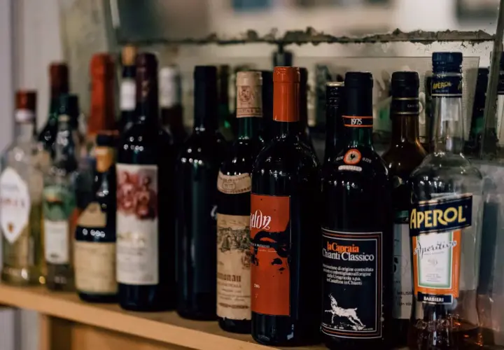 Rząd butelek wina, w tym Chianti Classico, i Aperol. Zastanawiasz się, ile wina można przewieźć z Włoch?