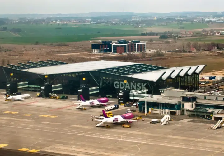 Samoloty Wizz Air i Lufthansa na płycie lotniska Gdańsk. W tle nowoczesny terminal i krajobraz.