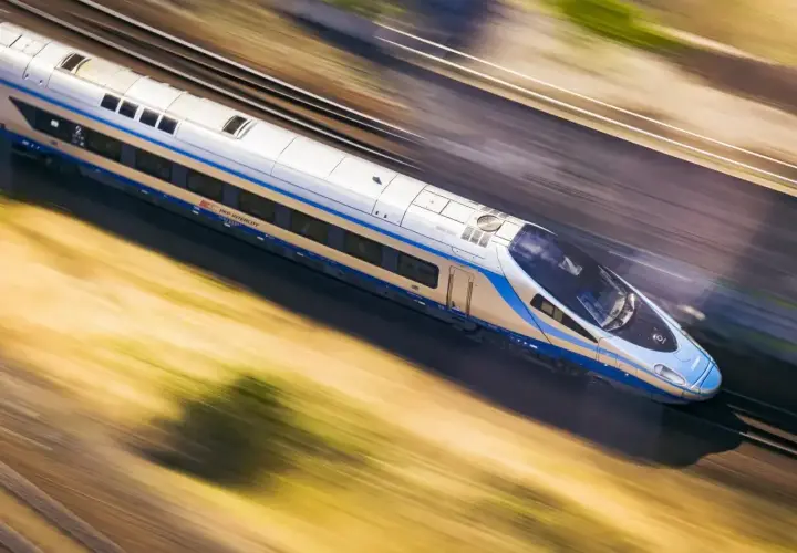 Pociąg PKP Intercity pędzi z ogromną prędkością, rozmazując krajobraz.
