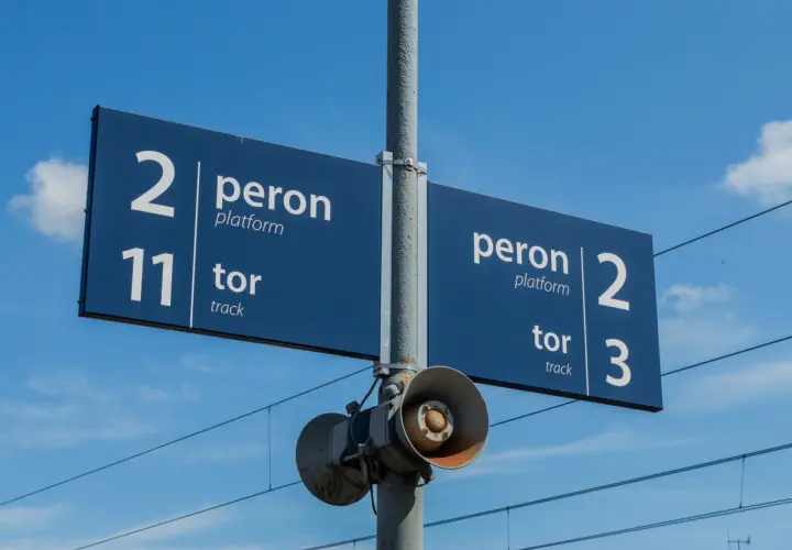Niebieska tablica informacyjna na dworcu kolejowym wskazuje peron 2, tor 11 oraz peron 2, tor 3.