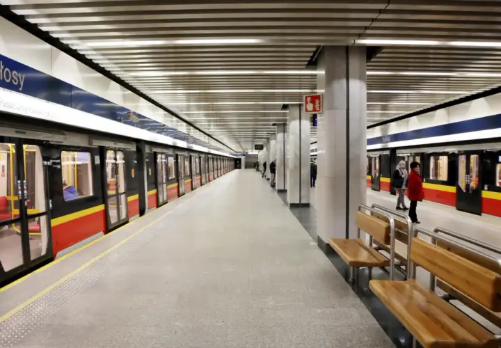 Stacja metra Stokłosy w Warszawie. Pociągi z czerwono-żółtymi pasami czekają na pasażerów.