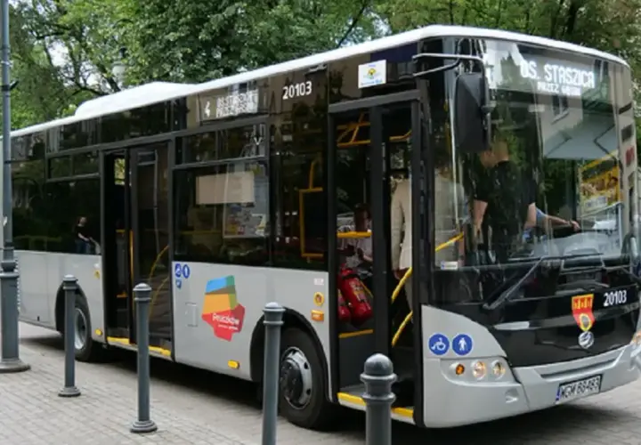 Autobus linii nr 6 Pruszków-Ożarów z numerem bocznym 20103 stoi na przystanku. Drzwi są otwarte, widać pasażerów.