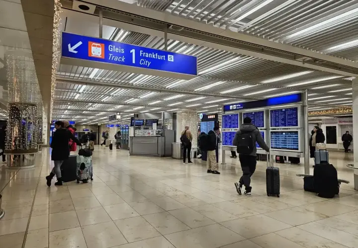 Wnętrze dworca kolejowego na lotnisku Frankfurt nad Odrą. Pasażerowie z bagażami czekają na pociąg do Frankfurtu.