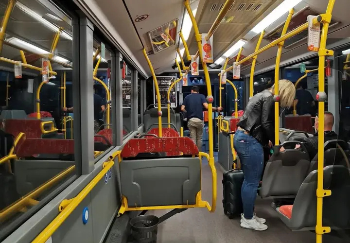 Wnętrze autobusu, żółte poręcze, siedzenia, pasażerowie z bagażem. Zadar komunikacja miejska.