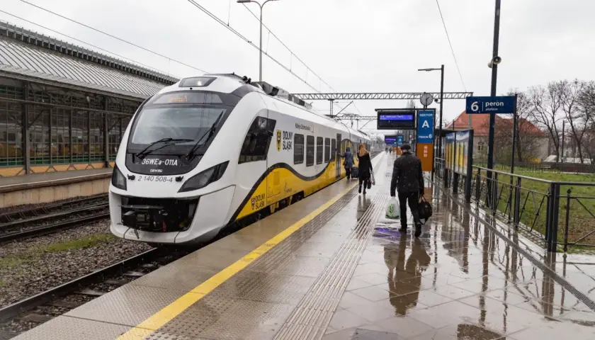 Pasażerowie wsiadają do pociągu, a obok stoi hulajnoga elektryczna.