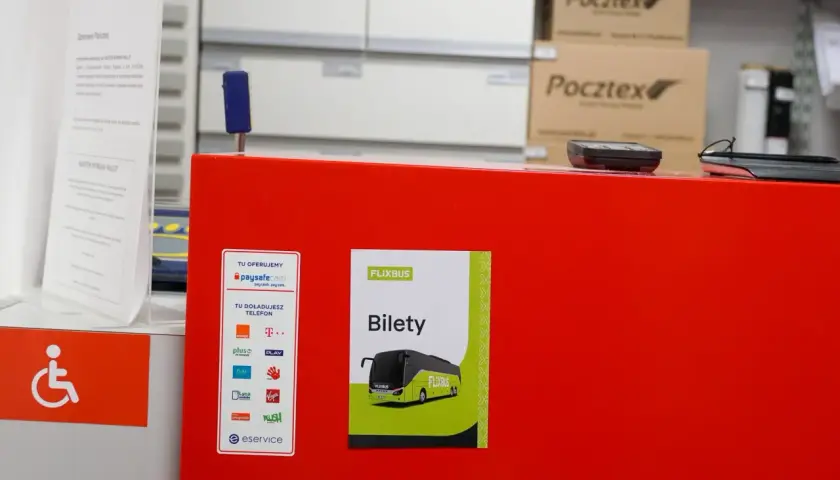 Na czerwonym blacie znajduje się plakat z napisem "FLIXBUS Bilety". To miejsce, gdzie kupisz bilet na Flixbus.
