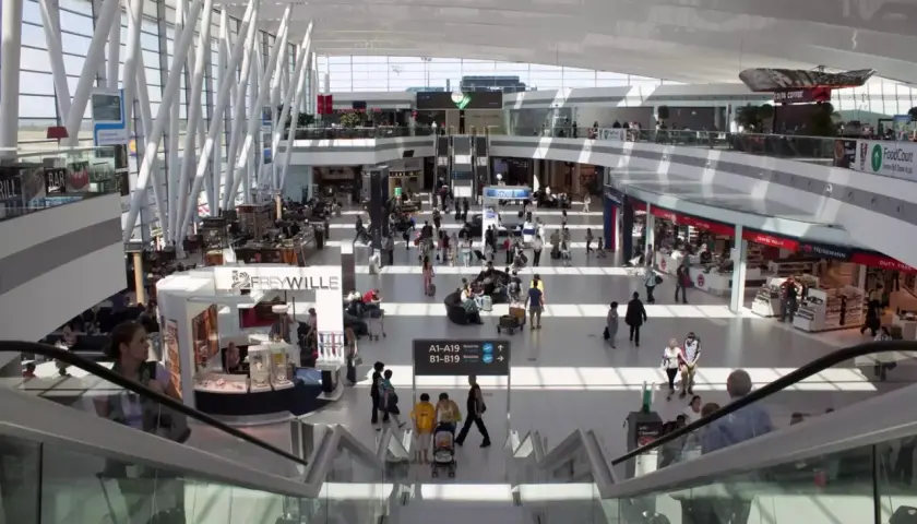 Tętniący życiem terminal lotniska w Budapeszcie. Ludzie poruszają się po nowoczesnej przestrzeni, szukając transportu z lotniska, sklepów i kawiarni.