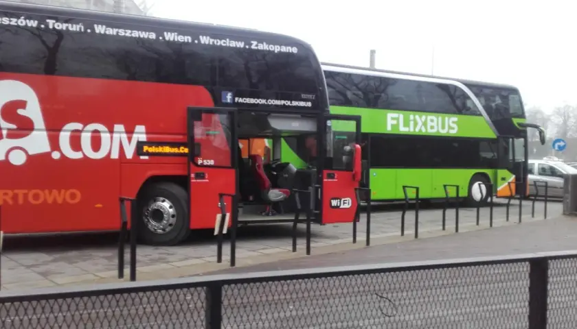 Dwa autokary Flixbus stoją obok siebie. Czerwony autokar ma otwarte drzwi, a zielony autokar z napisem FLIXBUS oferuje zniżki dla emerytów.