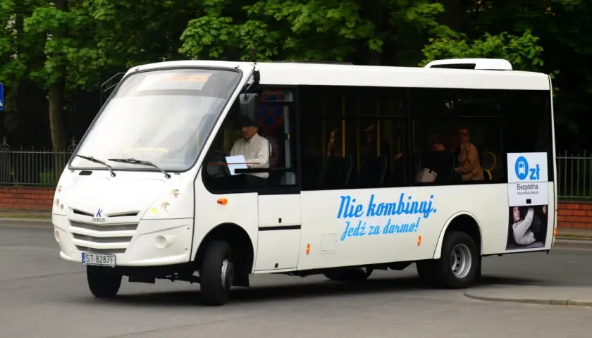 Białe autobusy w Żorach oferują bezpłatną komunikację miejską. Kierowca i pasażerowie w środku.