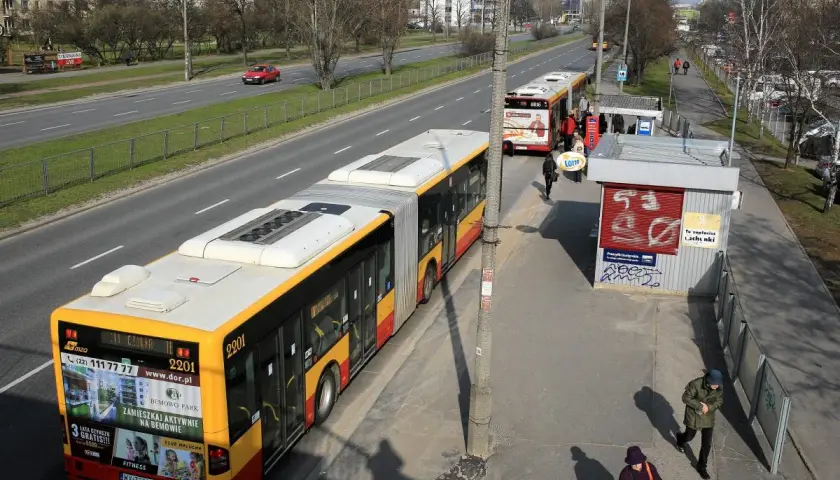 Autobus linii 702 Poznań na przystanku. Zbliża się do zatoczki, gdzie czekają pasażerowie.