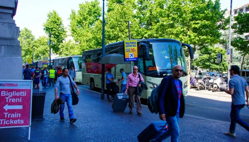 Autobus na lotnisko Malpensa, niedaleko jeziora Como. Ludzie z walizkami czekają na transport.