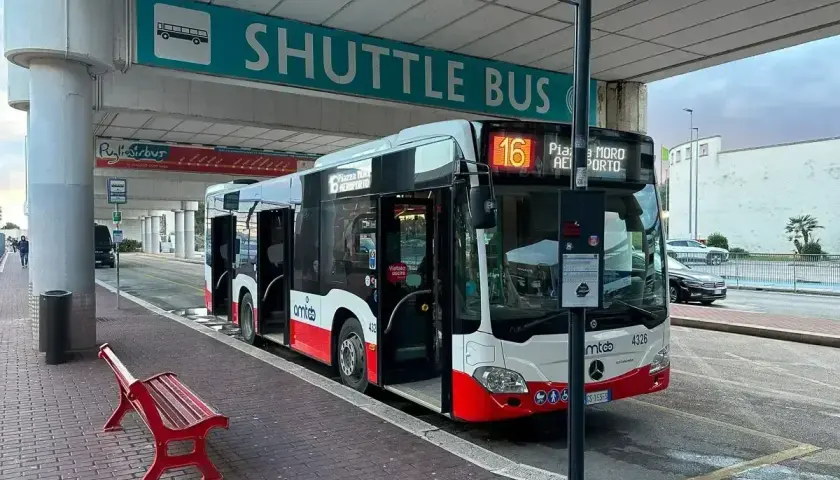 Autobus wahadłowy na lotnisku Bari czeka na pasażerów pod zielonym znakiem "SHUTTLE BUS".