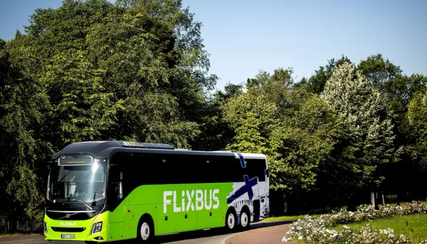 Zielony Flixbus na tle zieleni i błękitnego nieba. Piękne miejsce na podróż.