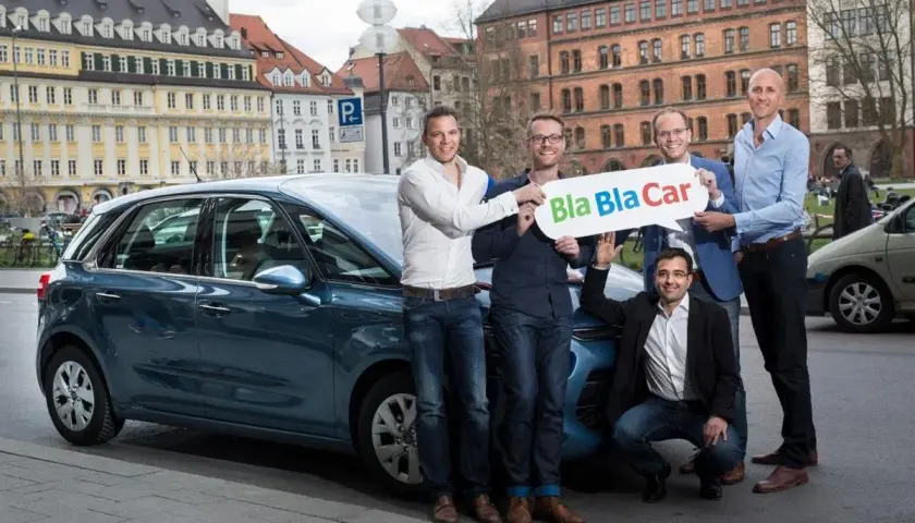 Zespół prezentuje, jak działa BlaBlaCar, stojąc obok samochodu.