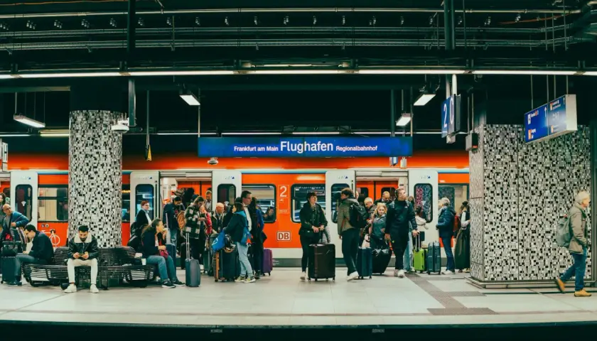 Ludzie z bagażami czekają na pociąg na stacji Regionalbahnhof na lotnisku we Frankfurcie.