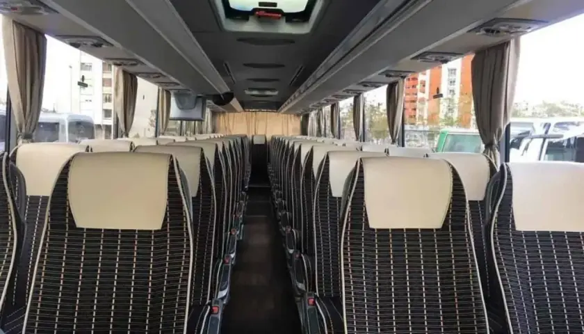Wnętrze autobusu ze Słowenii, rzędy wygodnych siedzeń z czarno-białą tapicerką i jasnymi zagłówkami.