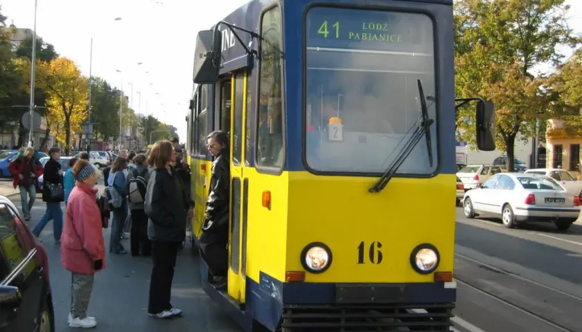 Żółto-niebieski tramwaj linii 41 Łódź Pabianice stoi na przystanku, czekając na pasażerów.