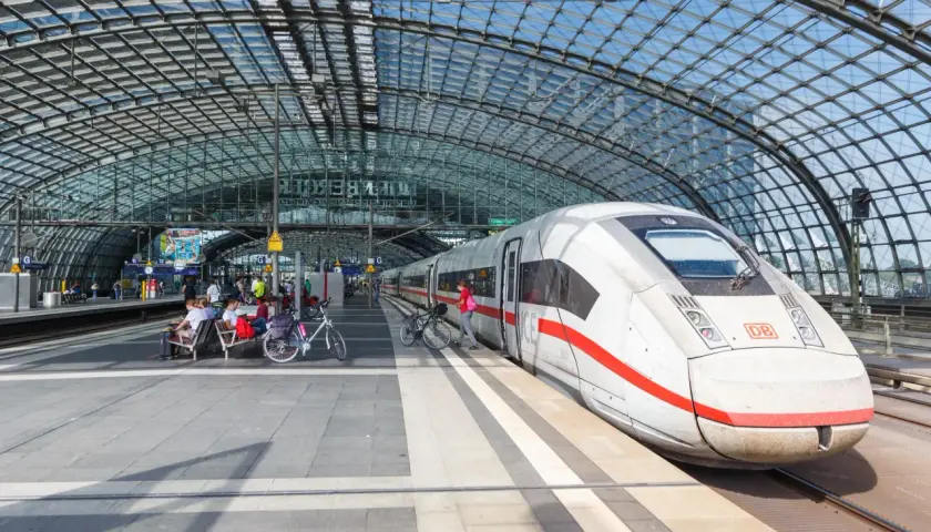 Biały pociąg ICE na peronie pod szklanym dachem. Berlin Dworzec Główny, ludzie czekają na pociąg z rowerami.