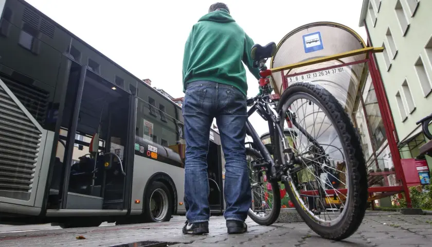 Mężczyzna z rowerem czeka na autobus.