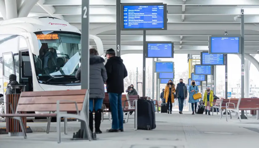 Na dworcu w Katowicach, przy tablicy z odjazdami, ludzie czekają na autobusy. Sprawdź rozkład, by dowiedzieć się, jak dojechać z dworca w Katowicach na Medyków.