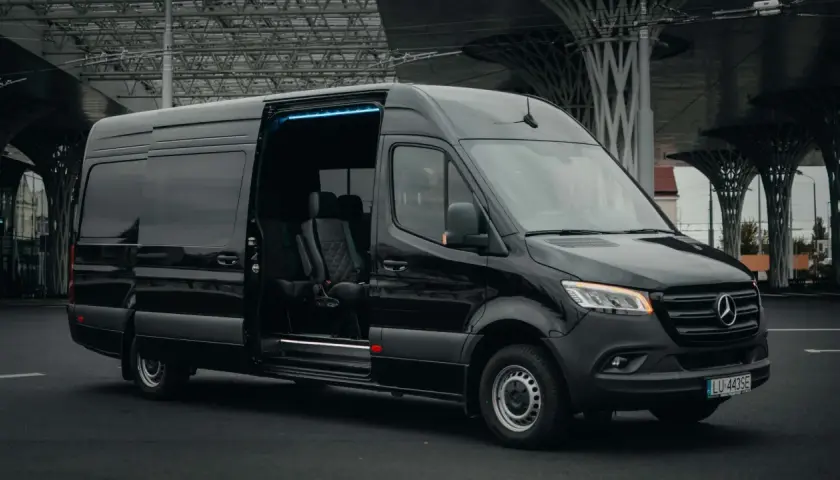 Czarny bus z Niemiec do Polski, z adresu pod adres. Komfortowe fotele i niebieskie oświetlenie wnętrza.