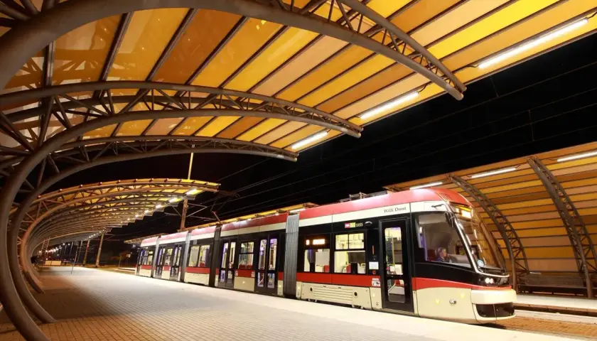 Nowoczesne gdynia tramwaje na peronie pod żółtą, łukowatą wiatą.