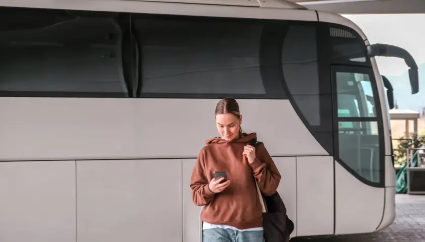 Młoda kobieta z telefonem czeka na autobus, który ma awarię taboru.