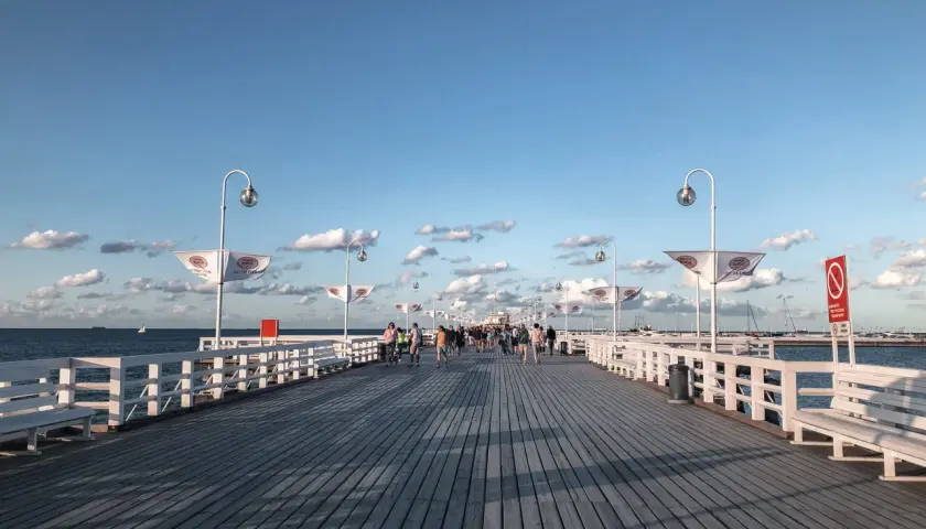 Spacer po molo w Sopocie, idealne miejsce na spacer po przyjeździe z Gdańska. Widać ludzi, ławki i latarnie.