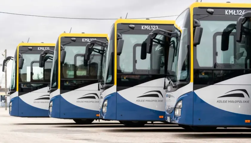 Rząd autobusów Kolei Małopolskich czeka na pasażerów. Busy te obsługują trasę Kraków - Sułkowice, zapewniając sprawne połączenie.