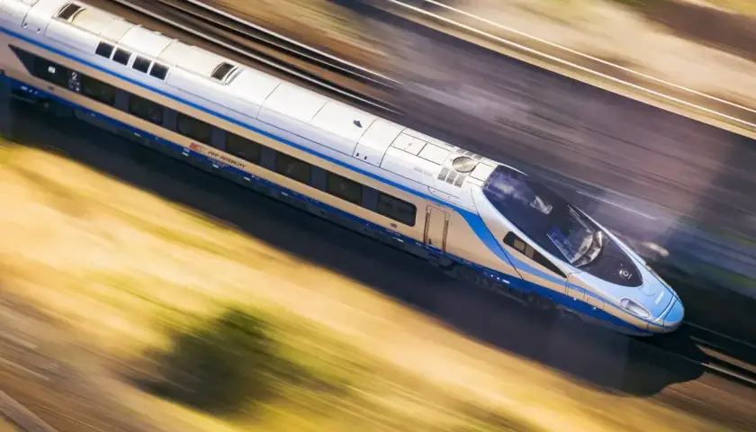 Pociąg PKP Intercity pędzi z ogromną prędkością, rozmazując krajobraz.