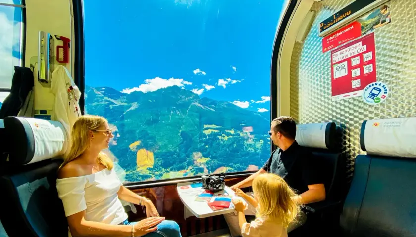 Rodzina podziwia alpejskie widoki przez okno pociągu Bernina Express. Bilety na tę podróż to gwarancja niezapomnianych wrażeń.