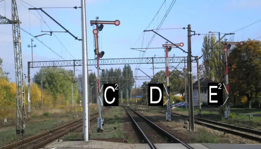 Semafor kolejowy z tarczą i światłami, wskazujący drogę pociągom.