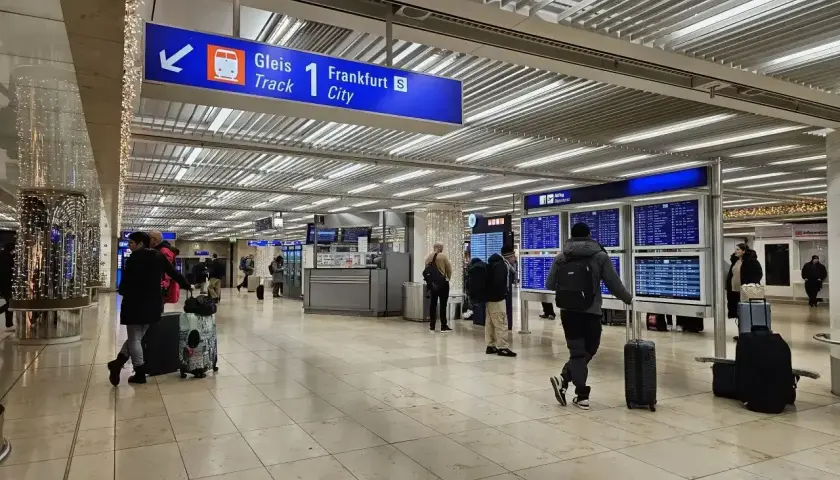 Wnętrze dworca kolejowego na lotnisku Frankfurt nad Odrą. Pasażerowie z bagażami czekają na pociąg do Frankfurtu.