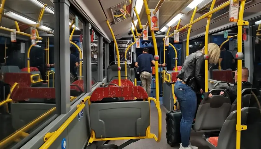 Wnętrze autobusu, żółte poręcze, siedzenia, pasażerowie z bagażem. Zadar komunikacja miejska.