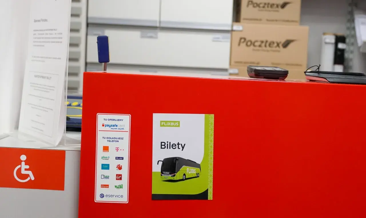 Na czerwonym blacie znajduje się plakat z napisem "FLIXBUS Bilety". To miejsce, gdzie kupisz bilet na Flixbus.
