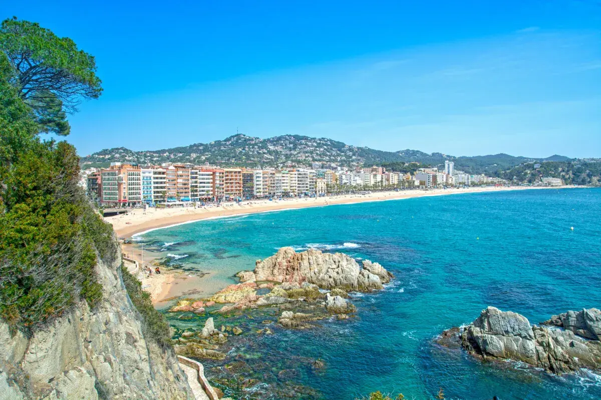 Widok na plażę w Lloret de Mar z klifów. W oddali widać zabudowania i wzgórza. Idealne miejsce na wakacje, niedaleko od lotniska.