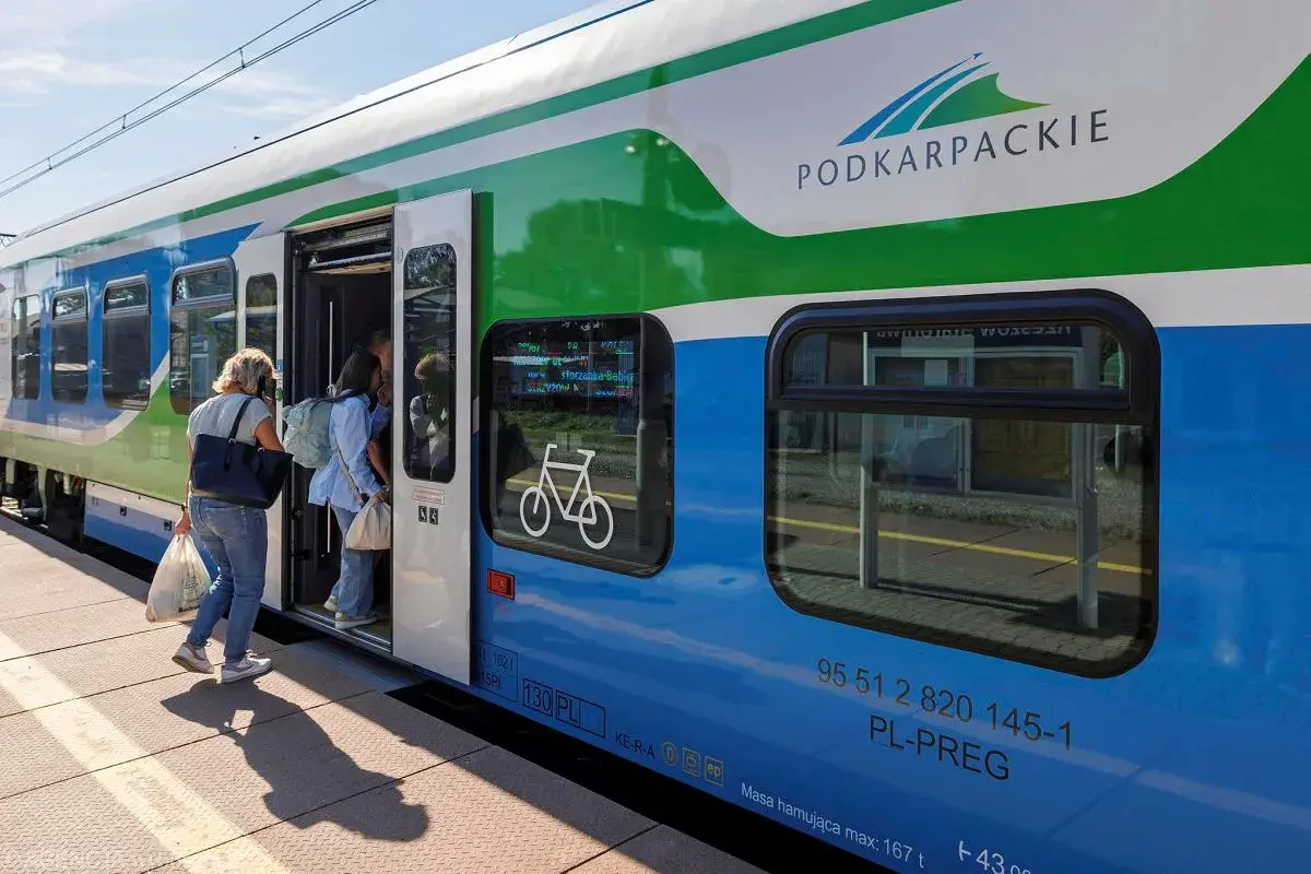 Pasażerowie wsiadają do pociągu Podkarpackiej Kolei Aglomeracyjnej. Na drzwiach widnieje symbol roweru.