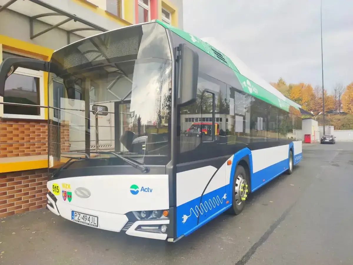 Nowoczesny ebus z numerem 515, ozdobiony zielonymi liśćmi i symbolem wtyczki, gotowy do ekologicznego transportu.