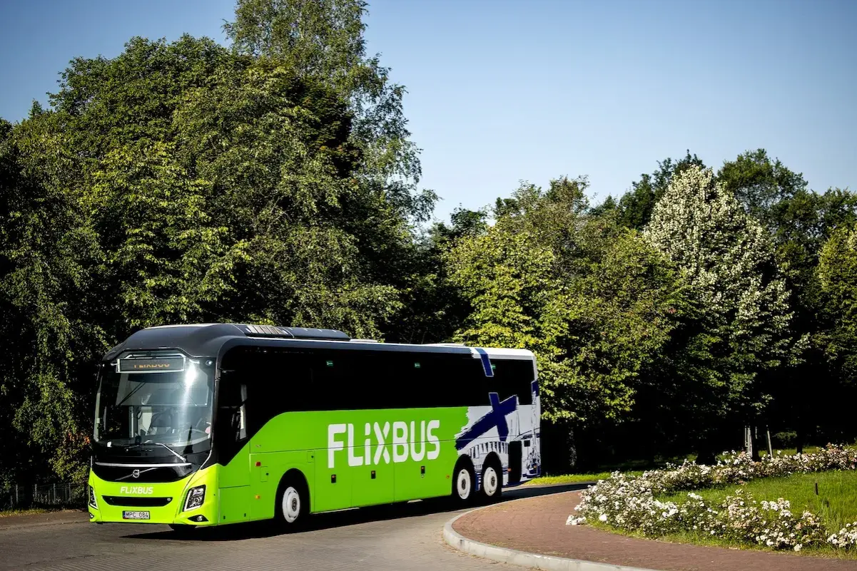 Zielony Flixbus na tle zieleni i błękitnego nieba. Piękne miejsce na podróż.