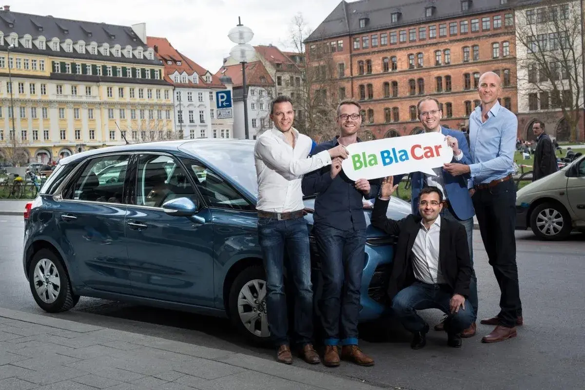 Zespół prezentuje, jak działa BlaBlaCar, stojąc obok samochodu.