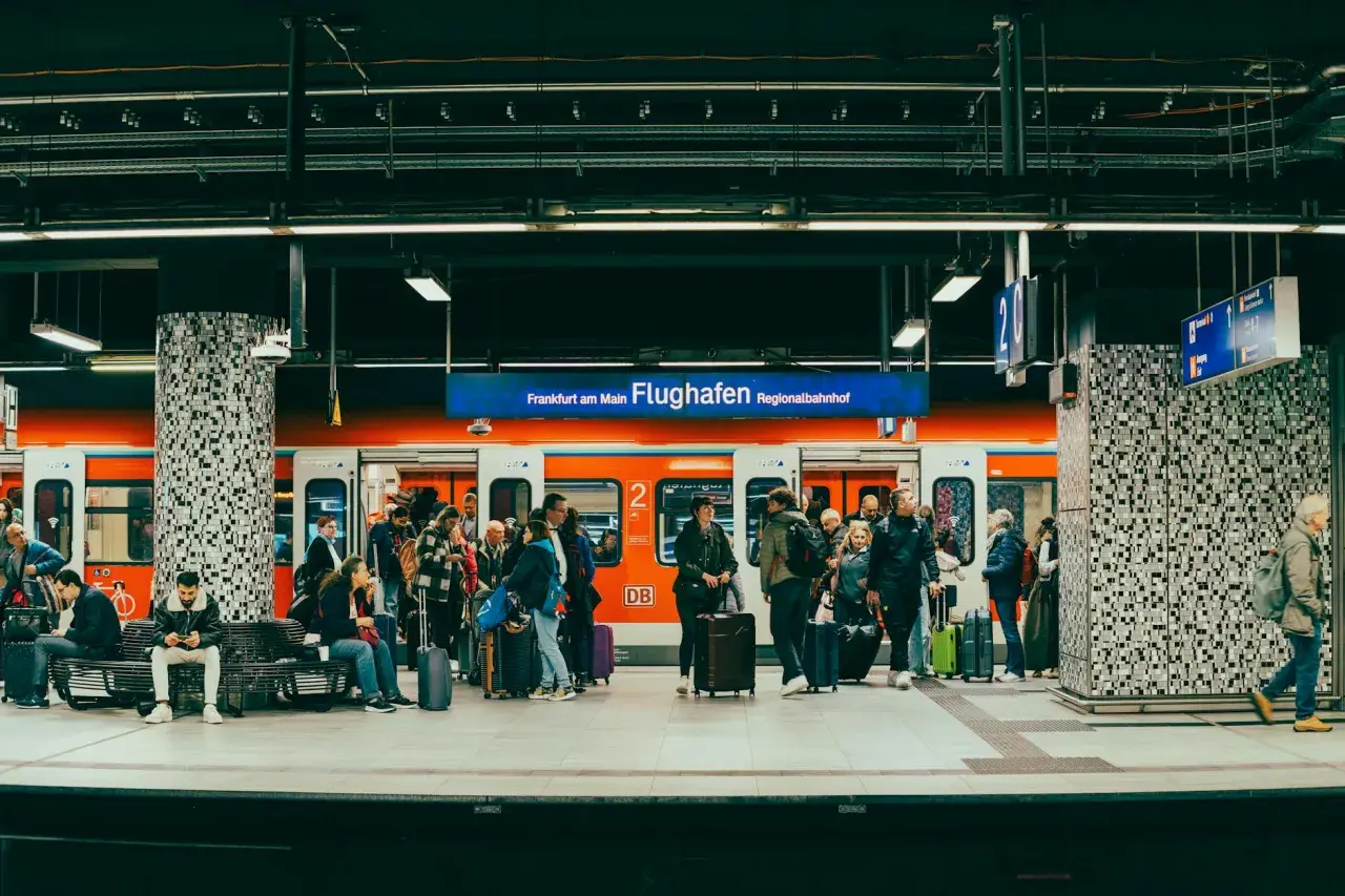 Ludzie z bagażami czekają na pociąg na stacji Regionalbahnhof na lotnisku we Frankfurcie.