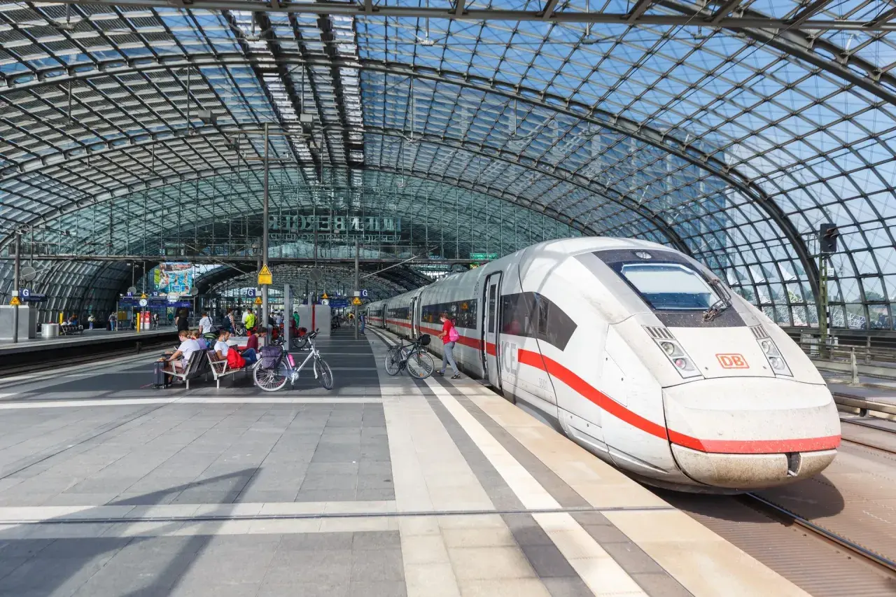 Biały pociąg ICE na peronie pod szklanym dachem. Berlin Dworzec Główny, ludzie czekają na pociąg z rowerami.